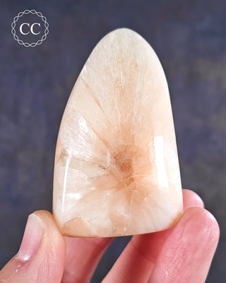 A hand holding a Peach Stilbite Freeform from India 