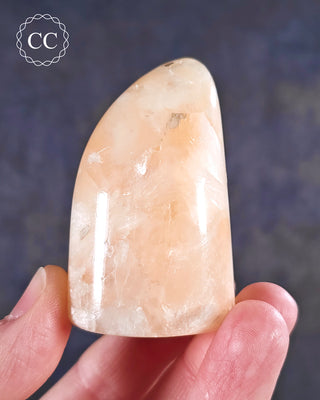 A hand holding a Peach Stilbite Freeform from India 