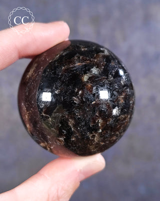 A hand holding a Phlogopite Mica Sphere