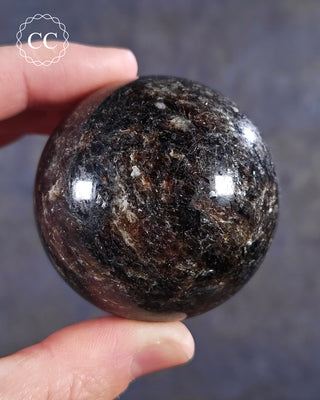A hand holding a Phlogopite Mica sphere 