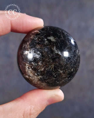 A hand holding a Phlogopite Mica sphere 