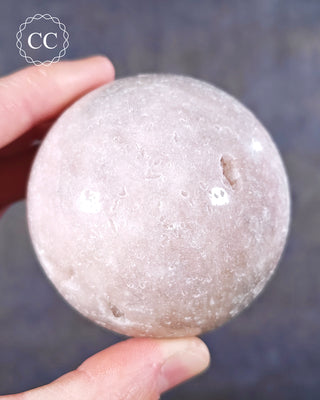 A hand holding a Pink Amethyst Sphere from Brazil