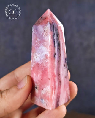 A hand holding a Pink Andean Opal Tower from Peru