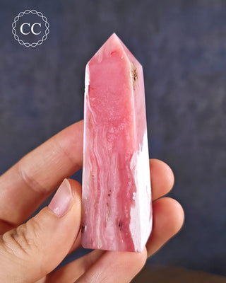 A hand holding a Pink Andean Opal Tower from Peru
