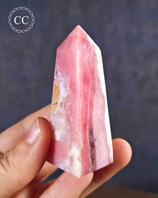 A hand holding a Pink Andean Opal Tower from Peru
