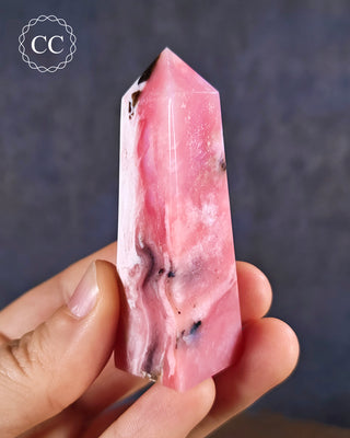 A hand holding a Pink Andean Opal Tower from Peru