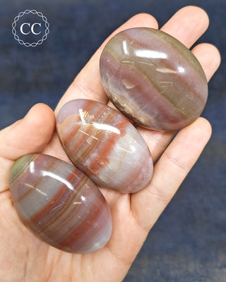 Pink Banded Calcite Palm Stones in hand