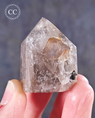 A hand holding  a Pink Hematite (Lithium) Quartz Tower from Brazil 