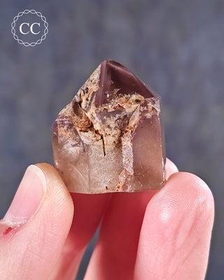 A hand holding  a Pink Hematite (Lithium) Quartz Tower from Brazil 