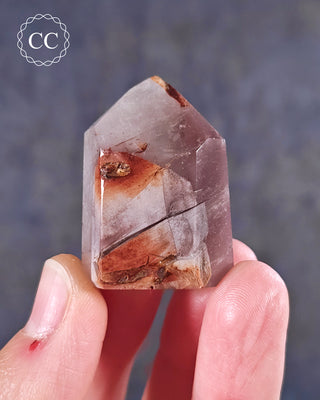 A hand holding  a Pink Hematite (Lithium) Quartz Tower from Brazil 