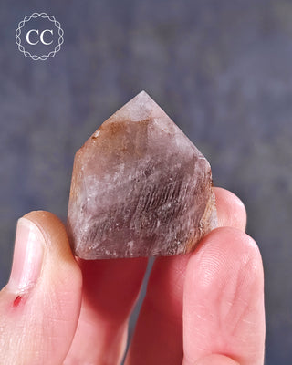 A hand holding a Pink Phantom Quartz Tower from Brazil 