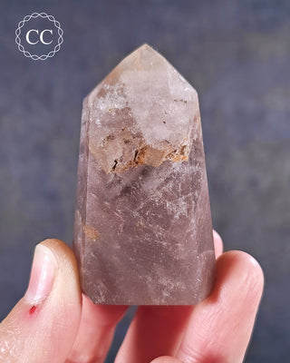 A hand holding a Pink Phantom Quartz Tower from Brazil 