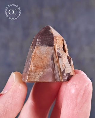 A hand holding a Pink Phantom Quartz Tower from Brazil 