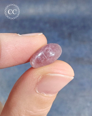 A hand holding a Pink Tourmaline Cabochon from Siberia 