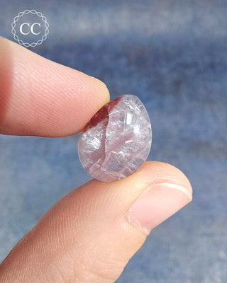 A hand holding a Pink Tourmaline Cabochon from Siberia 