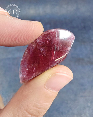 A hand holding a Pink Tourmaline Cabochon from Siberia 