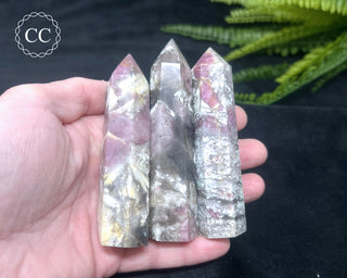 A hand holding 3 Pink Tourmaline towers