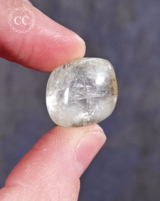 A hand holding a polished Green Apophyllite crystal