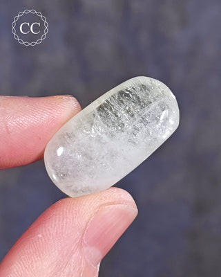 A hand holding a polished Green Apophyllite crystal