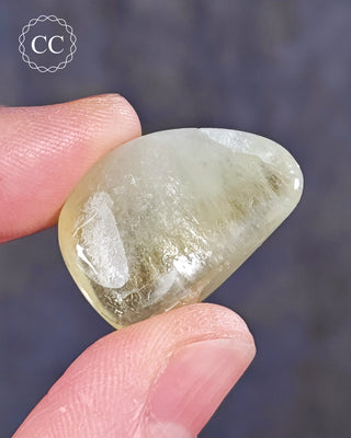 A hand holding a polished Green Apophyllite crystal