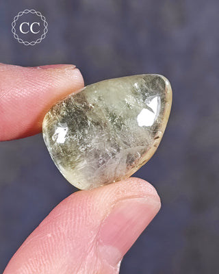 A hand holding a polished Green Apophyllite crystal