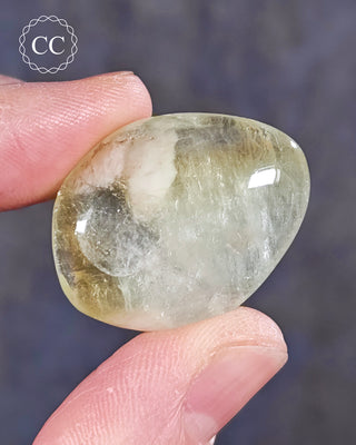 A hand holding a polished Green Apophyllite crystal