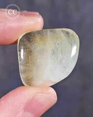 A hand holding a polished Green Apophyllite crystal