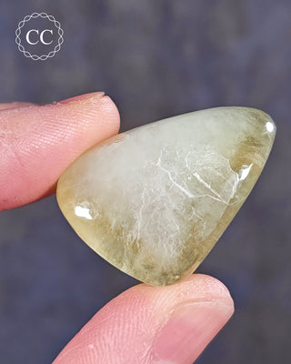A hand holding a polished Green Apophyllite crystal
