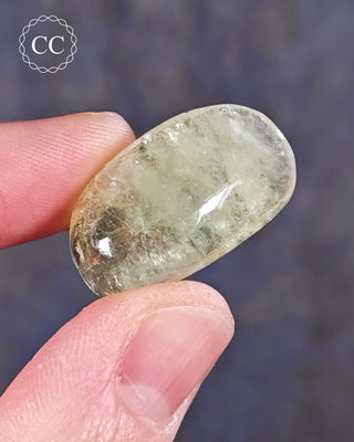 A hand holding a polished Green Apophyllite crystal