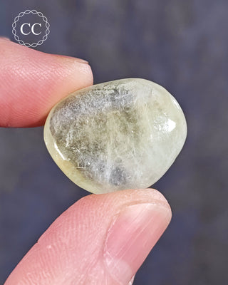 A hand holding a polished Green Apophyllite crystal