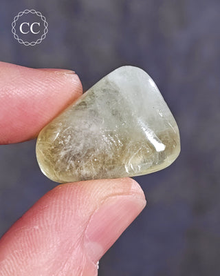 A hand holding a polished Green Apophyllite crystal