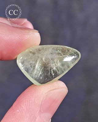 A hand holding a polished Green Apophyllite crystal