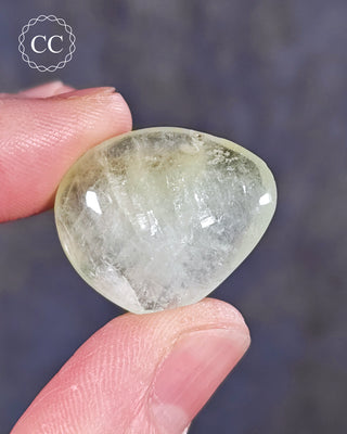 A hand holding a polished Green Apophyllite crystal