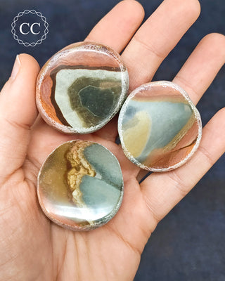 A hand holding 3 Polychrome Jasper Dragon Eggs from Madagascar
