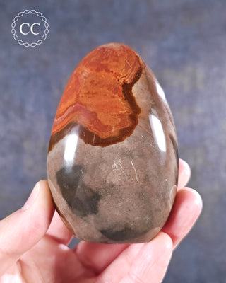 A hand holding a Polychrome Jasper Sphere from Madgascar