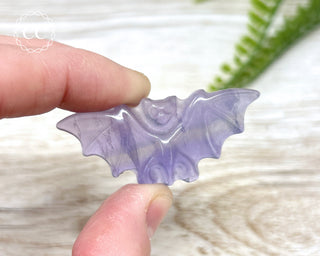 Finger holding one Purple Fluorite Bat 