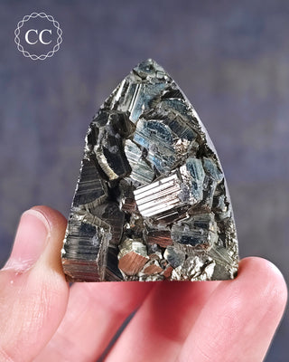 A hand holding a part polished Pyrite Freeform from Peru