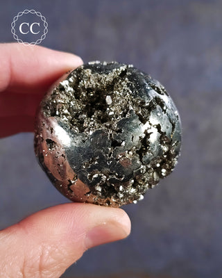 A hand holding a Pyrite sphere from Brazil 