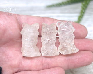 A hand holding 3 Quartz Fox Carvings
