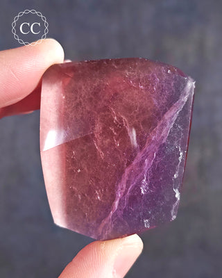 A hand holding a bright coloured Rainbow Fluorite Freeform 