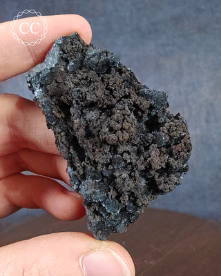 A hand holding a specimen of Romanechite from Santa Eulalia, Mexico