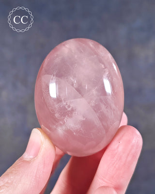  A hand holding a Rose Quartz palm stone from Madagascar