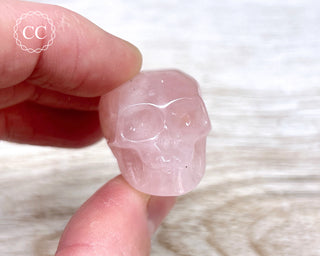 Fingers holding a Rose Quartz crystal skull carving