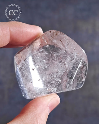 A hand holding a  polished rutilated Quartz freeform from Brazil 