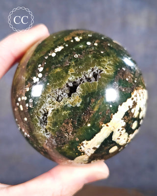 A hand holding a Sea Jasper Sphere from Madagascar