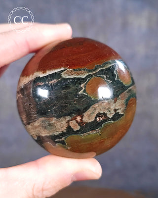 A hand holding a Sea Jasper Sphere from Madagascar