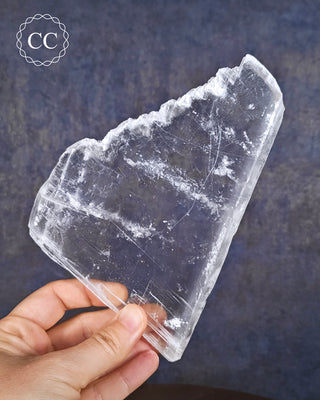 A hand holding an unpolished Selenite Window plate
