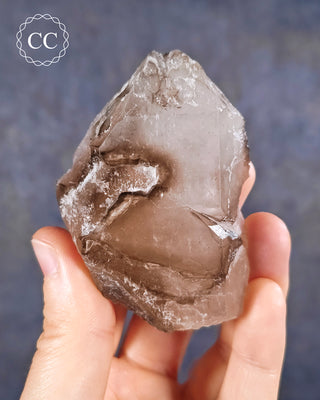 A hand holding an Smoky Elestial Quartz from Brazil