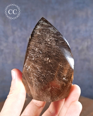 Smoky Quartz flame in hand on blue background