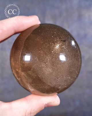 A hand holding a Smoky Quartz sphere from Madagascar